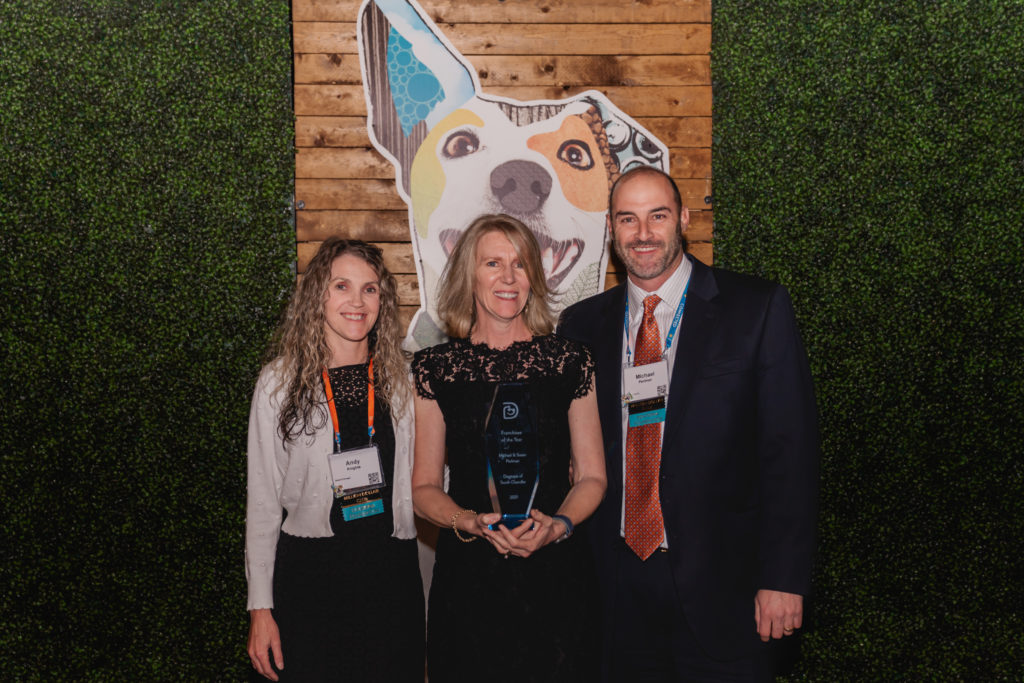 Franchisees holding award in front of Dogtopia dog imagery