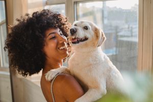 Woman holding dog indoors by a window